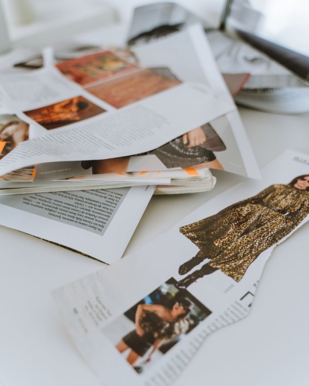 책상 위에 찢어 놓은 패션 잡지 페이지들을 가까이서 찍은 사진.